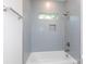 Bright bathroom with gray tiling surrounding tub, shower niche and window at 1724 Dallas Ave, Charlotte, NC 28205