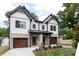 A view of a modern, two-story home with a well-manicured lawn, gray brick and wood garage doors at 1728 Dallas Ave, Charlotte, NC 28205