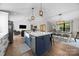 Open-concept kitchen flows to the dining and living rooms with white cabinetry, a blue island, and modern appliances at 17403 Green Hill Rd, Charlotte, NC 28278