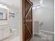Bathroom with a rustic wooden barn door, toilet, shower, and vanity at 1925 Sandal Brook Rd, Indian Land, SC 29707