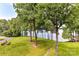 Beautiful backyard with sloping green lawn and mature trees that overlook views of the lake at 303 Northwest Dr, Davidson, NC 28036