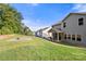 Large backyard with lush green grass, a stone fire pit, and a covered porch overlooking the yard at 3212 Gilroy Dr, Fort Mill, SC 29707