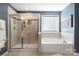 Bathroom featuring tiled shower with glass door and a soaking tub beneath a window at 3212 Gilroy Dr, Fort Mill, SC 29707