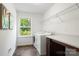 Bright laundry room with modern washer and dryer, shelving, dark wood cabinets and a sunlit window at 3212 Gilroy Dr, Fort Mill, SC 29707