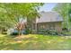 Large backyard with a wooden deck, green lawn, mature trees, and a black fence at 4075 Crepe Ridge Dr, Denver, NC 28037