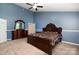 This primary bedroom has blue walls, a decorative bed frame, a ceiling fan, and neutral carpet at 4201 Amber Leigh Way Dr, Charlotte, NC 28269