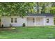 Charming single-story home with a brick facade and a cozy front porch, surrounded by lush greenery and a well-maintained lawn at 4410 Burgin St, Kannapolis, NC 28081