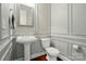 Elegant powder room with a pedestal sink, paneled walls, and dark wood floors at 463 Langston Place Dr, Fort Mill, SC 29708