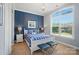 Charming bedroom with a queen bed, blue accent wall, carpet and a sun-filled arched window at 463 Langston Place Dr, Fort Mill, SC 29708