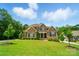 Beautiful two-story brick home featuring a well-manicured lawn and mature trees against a bright blue sky at 463 Langston Place Dr, Fort Mill, SC 29708