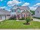 Charming two-story home featuring a well-manicured lawn, brick accents and red shutters at 511 Rough Hewn Ln, Rock Hill, SC 29730
