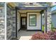 Inviting front porch with stone columns, black trim, and a view of the landscaped front yard at 6277 Raven Rock Dr, Denver, NC 28037