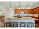 Kitchen island with granite countertops and barstool seating underneath pendant lights and wood cabinets at 6277 Raven Rock Dr, Denver, NC 28037