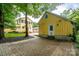Charming backyard with yellow house and brick-paved walkway, surrounded by lush greenery and mature trees at 660 Ideal Way, Charlotte, NC 28203