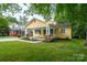 Charming yellow home boasts a welcoming front porch, lush lawn, and inviting curb appeal at 660 Ideal Way, Charlotte, NC 28203