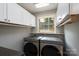 Laundry room with dual washer and dryer and white storage cabinets at 660 Ideal Way, Charlotte, NC 28203