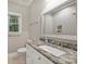 Well-lit bathroom featuring granite countertops, a white vanity, a shower, and serene outdoor views at 7117 Cobblecreek Dr, Weddington, NC 28104