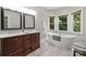 Elegant bathroom featuring dual vanities, a freestanding tub, and natural light from adjacent windows at 7117 Cobblecreek Dr, Weddington, NC 28104