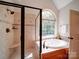 Elegant bathroom with a separate shower and soaking tub underneath a large window at 8101 Cane Pointe Ln, Waxhaw, NC 28173