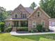 A stately brick home with a covered front porch, lush landscaping, and mature trees offers classic curb appeal at 8101 Cane Pointe Ln, Waxhaw, NC 28173