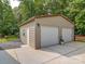 A detached two car garage with two white doors, concrete foundation and a small door on the side at 8101 Cane Pointe Ln, Waxhaw, NC 28173