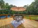 Outdoor wooden deck featuring a table and chairs with an umbrella, creating an ideal space for al fresco dining at 8101 Cane Pointe Ln, Waxhaw, NC 28173