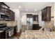 Modern kitchen with stainless steel appliances, granite countertops, dark wood cabinets, and open to the dining area at 9285 Swimming Dr, Harrisburg, NC 28075