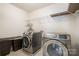 Functional laundry room with modern washer and dryer, shelving, and ample space for laundry tasks at 9285 Swimming Dr, Harrisburg, NC 28075