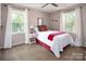 Well-lit bedroom with neutral tones, two windows, and a comfortable queen bed with red accents at 9928 Raddington Ln, Charlotte, NC 28269