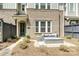 Close-up of a townhome's entrance with a gray patio set, brick facade, and a welcoming green door at 10022 Wayfair Meadow Ct, Charlotte, NC 28277