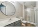 Bright bathroom featuring a stand up shower with glass doors, round mirror, and neutral wall paint at 10867 Garden Oaks Ln, Charlotte, NC 28273