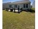 A well-manicured backyard featuring a patio with grill, lawn, shrubs, and green grass at 110 White Apple Way, Statesville, NC 28625