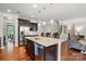 Kitchen island with seating, stainless steel refrigerator, hardwood floors, and view to the living room and stairs at 11070 River Oaks Nw Dr, Concord, NC 28027