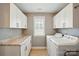 Well-lit laundry room with storage cabinets, granite countertop, and modern washer and dryer at 11070 River Oaks Nw Dr, Concord, NC 28027