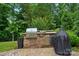 Built-in outdoor kitchen area featuring stone accents and a grill, surrounded by lush greenery at 11070 River Oaks Nw Dr, Concord, NC 28027