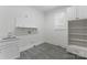 Modern laundry room with sink, storage cabinets, and gray tile flooring at 1108 Shinnecock Ln, Waxhaw, NC 28173