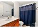 A bathroom features a wood vanity, white toilet, a shower with a blue curtain, and a mirror at 1134 Plaza Walk Dr, Charlotte, NC 28215