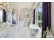 Bright bathroom with freestanding tub, marble floors, dual sinks, floral wallpaper, and natural light from a large window at 1172 Queens Rd, Charlotte, NC 28207