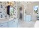 Bright bathroom with marble floors, patterned wallpaper, updated vanity, and frosted glass door at 1172 Queens Rd, Charlotte, NC 28207