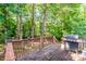 View of wooden back deck, with grill, overlooking lush green scenery at 125 Shenandoah Loop, Troutman, NC 28166