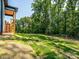 Expansive backyard with lush green grass leading up to mature trees and an elevated porch at 2004 Plain Field Dr, Bessemer City, NC 28016