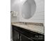 Well-lit bathroom featuring a granite countertop, oval mirror, and white shiplap accent wall at 228 Coneflower Pl, Fort Mill, SC 29708