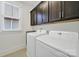 This laundry room features front-load machines, dark cabinetry, a window, and tiled floors at 228 Coneflower Pl, Fort Mill, SC 29708