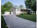 Home exterior showcasing a long driveway, partial stone facade, and complementary green shutters at 332 Daybrook Dr, Landis, NC 28088