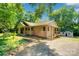 Charming home exterior with covered porch, surrounded by lush greenery, and a storage shed at 3333 Roberta Rd, Concord, NC 28027