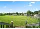 Expansive backyard with lush green grass, framed by a classic wooden fence and bright blue sky at 3340 Emerald Pointe Ct, Monroe, NC 28110
