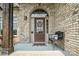 Inviting front porch featuring brickwork, a cozy bench, and a decorative front door at 3340 Emerald Pointe Ct, Monroe, NC 28110