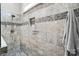 Detailed view of tiled shower with mosaic accents, rainfall shower head, and inset shelf at 3340 Emerald Pointe Ct, Monroe, NC 28110