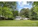 Large, grassy backyard surrounded by mature trees offers plenty of space for outdoor activities at 4929 Prentice Pl, Charlotte, NC 28210