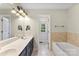 Well-lit bathroom with dual sinks, vanity, bathtub, and modern fixtures at 5410 Berryview Ln, Gastonia, NC 28056